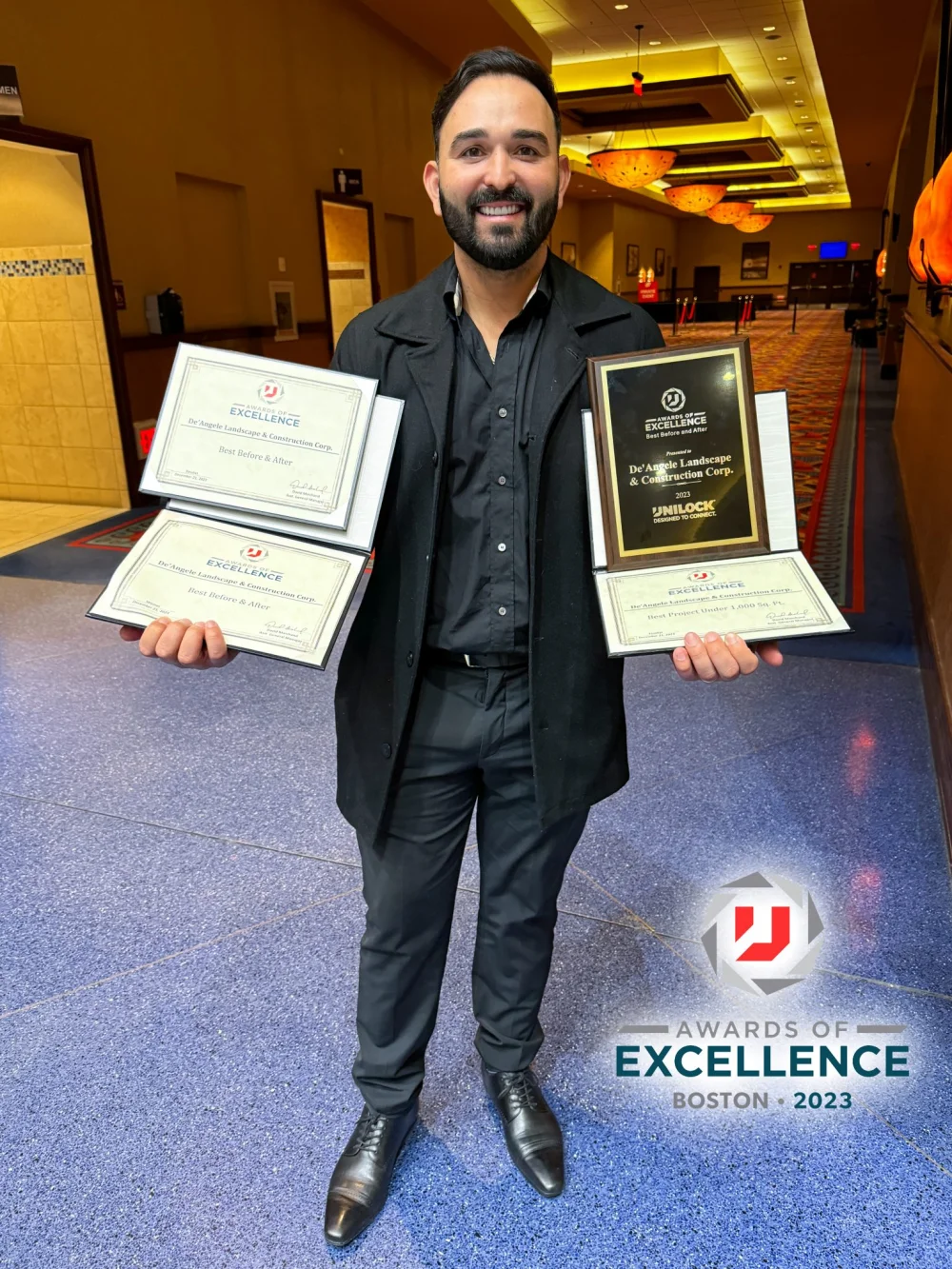De'Angele accepting the Unilock Awards of Excellence Boston 2023 certificates and plaque