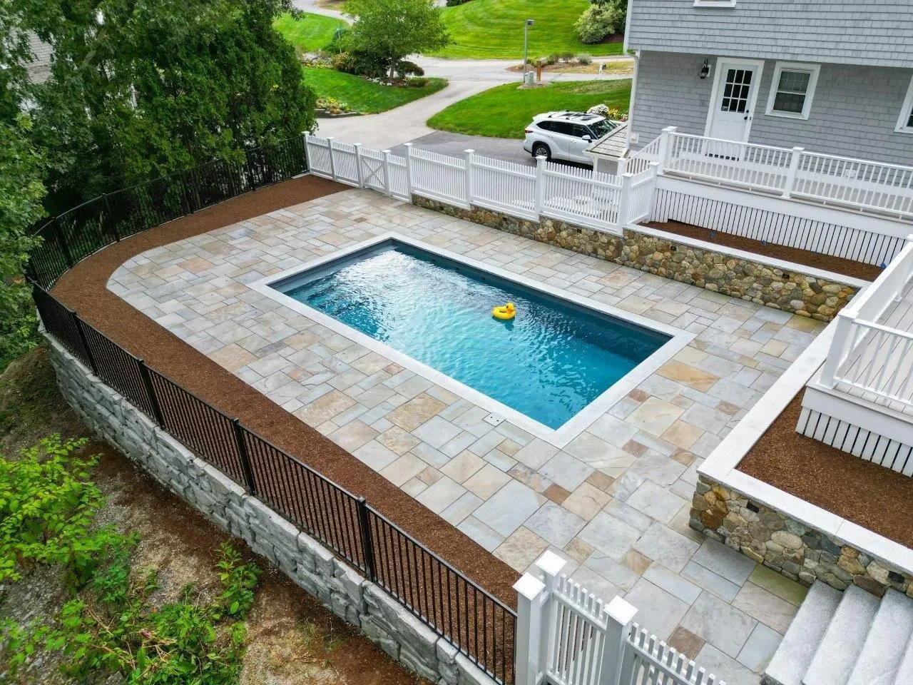 Aerial view of bluestone pool patio and curved stone retaining wall