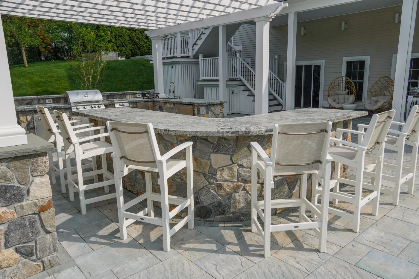 Outdoor kitchen bar seating area under pergola